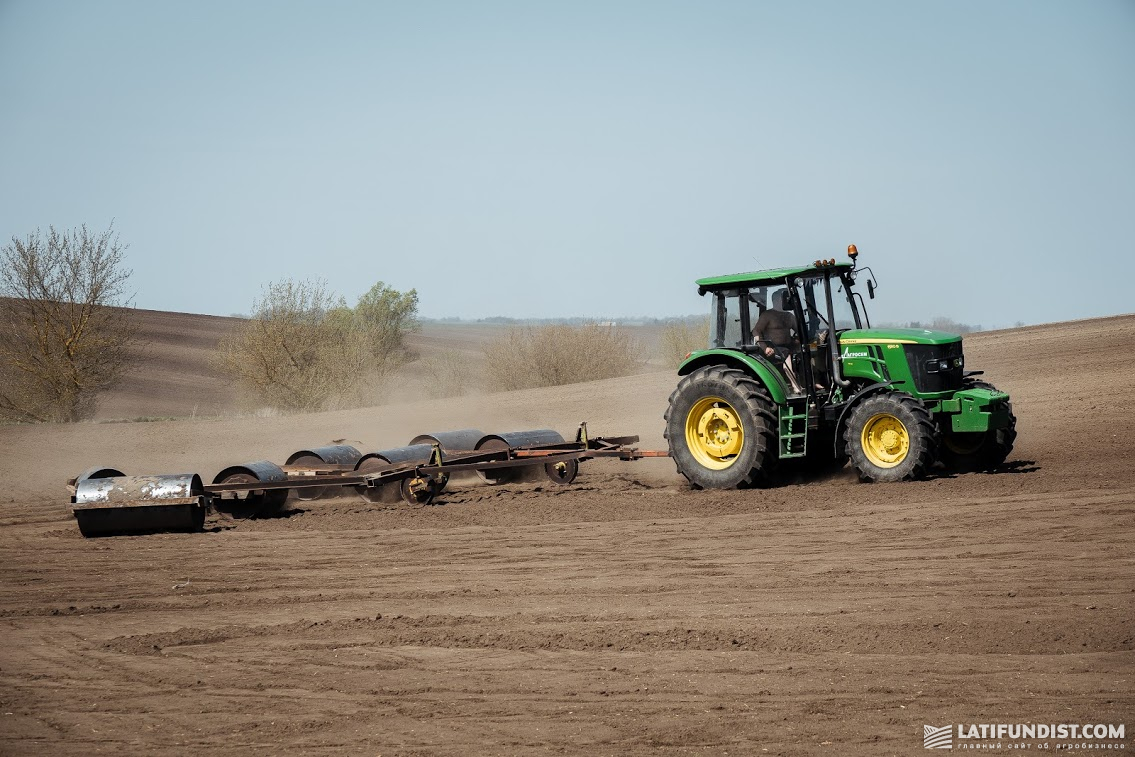 Трактор John Deere прикатывает посевы